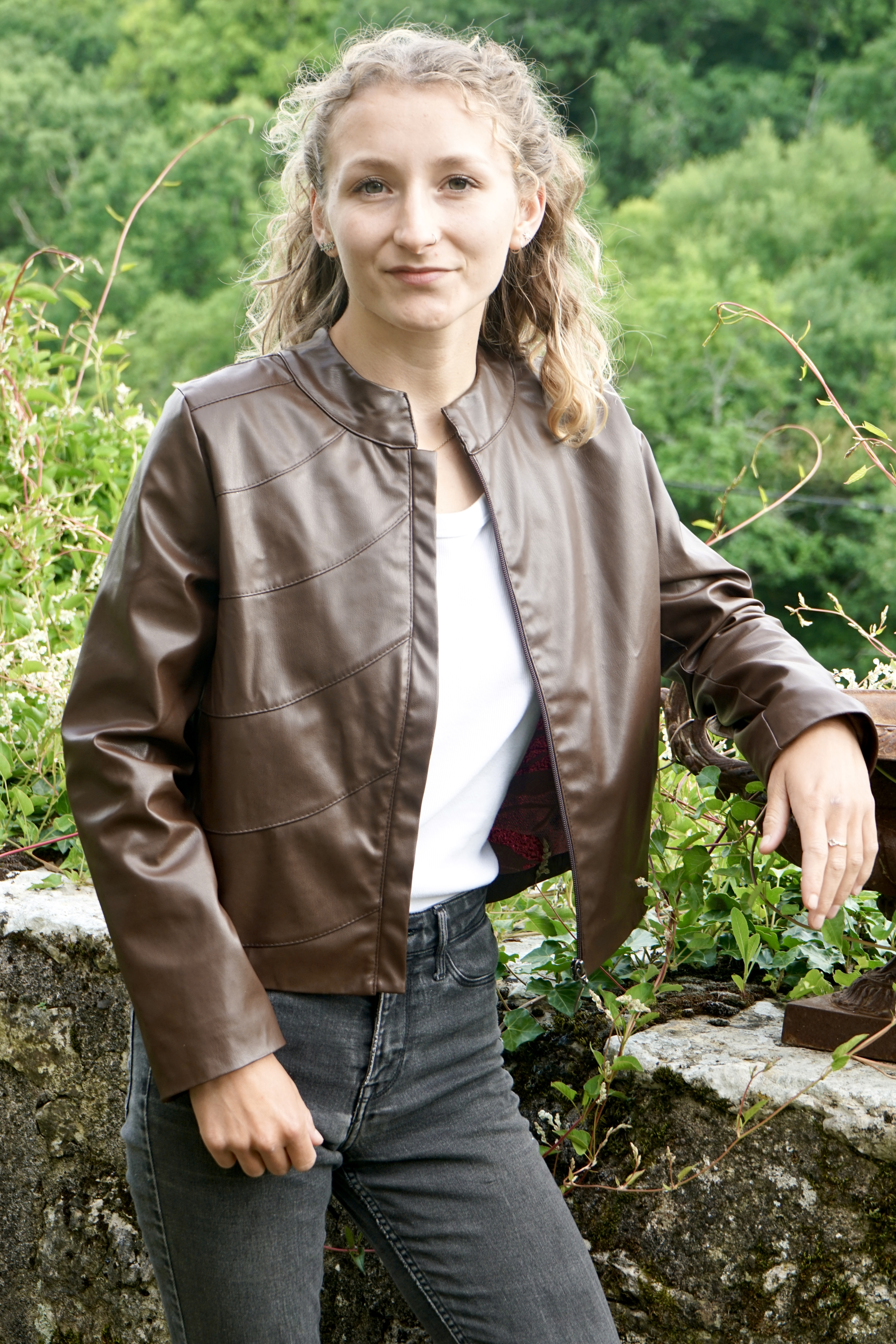 Model wearing luxury bespoke vegan leather jacket in chestnut brown   showing  the red flame lining and the quality of craftsmanship